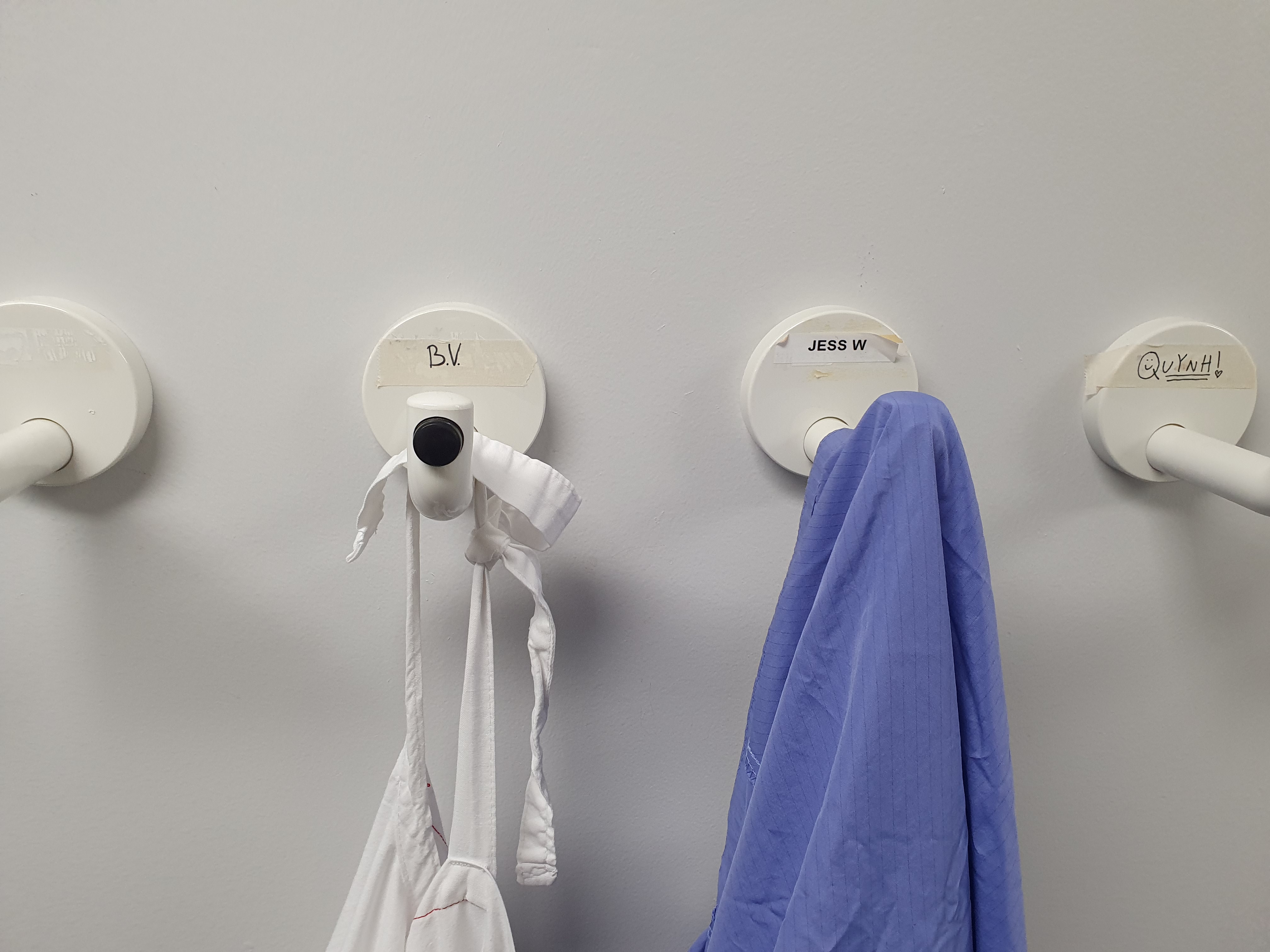 Lab coat hanging on a hook with initials 'BV'